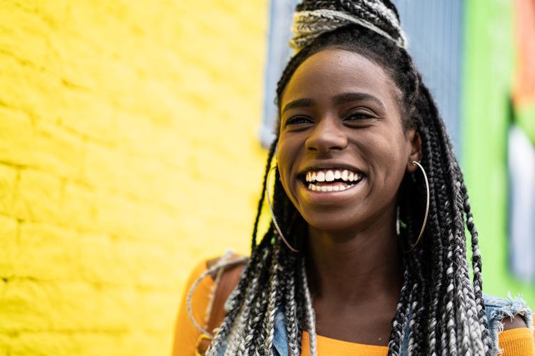 Young black woman laughing in vibrant coloured neighbourhood