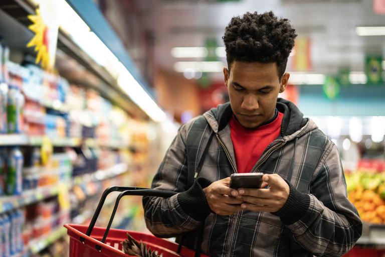 Man on phone shopping in a supermarket